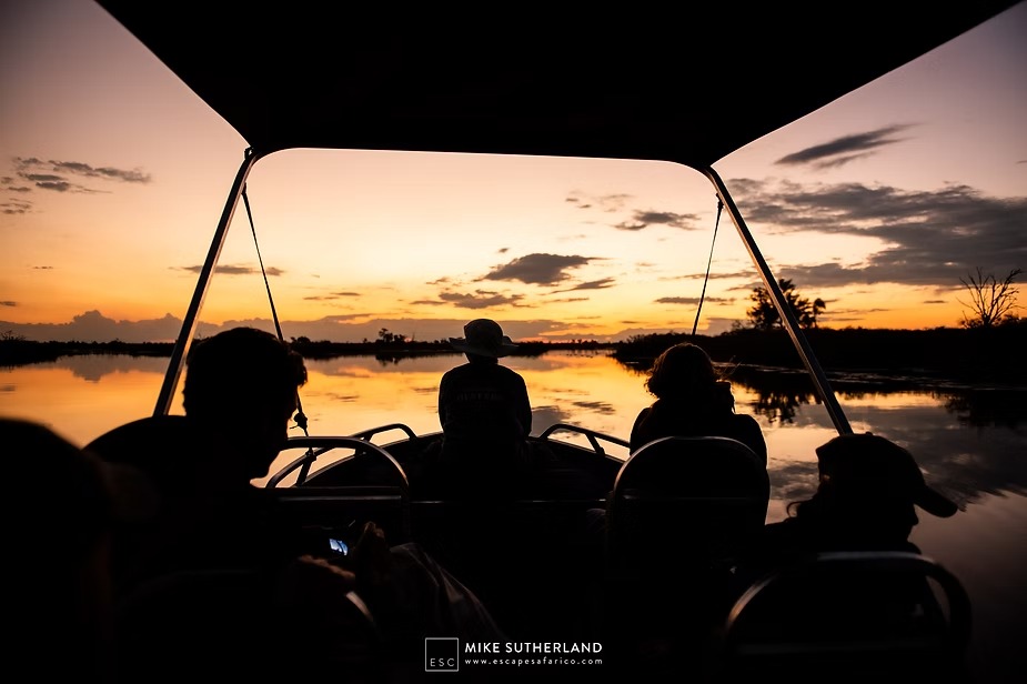 Guests silhouetted in the boat as the sun goes down over the lagoon