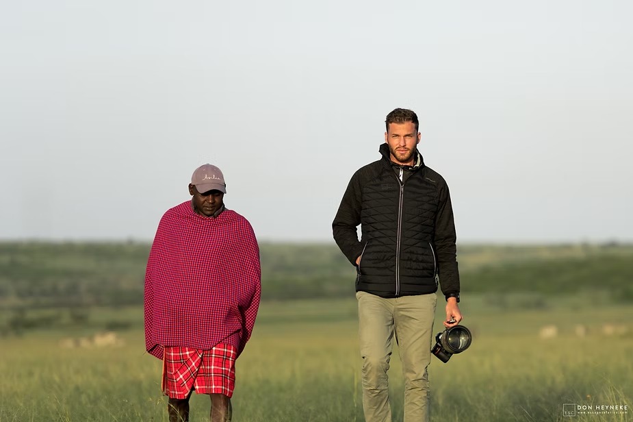 A Maasai guide walking out with a photographer across the conservancy