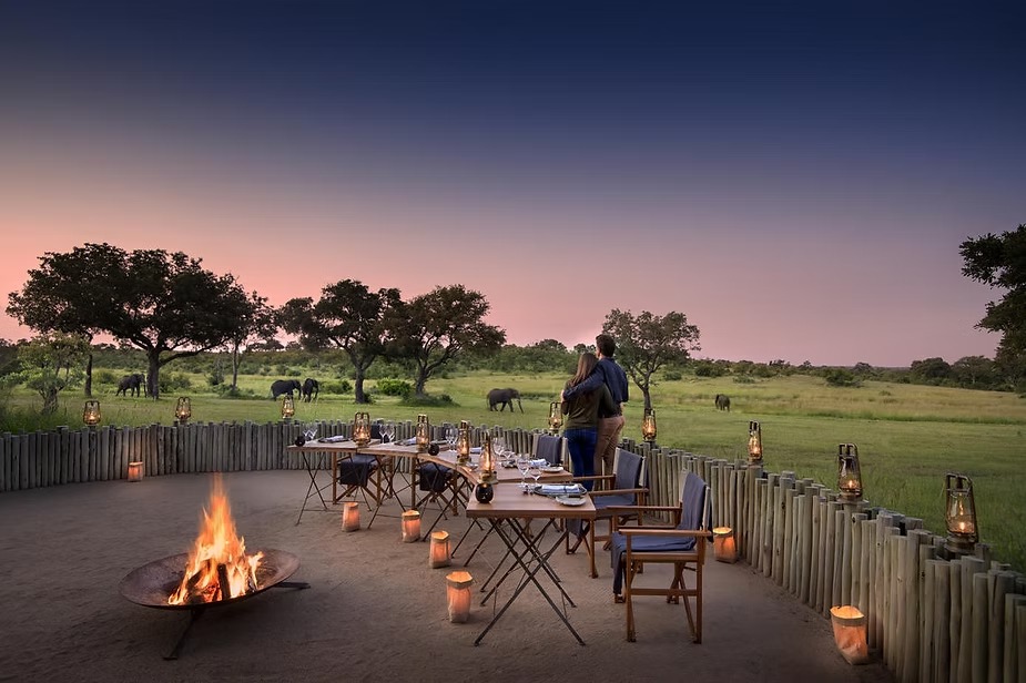 Dinner laid out around the fire at Singita Castleton with elephants feeding beyond