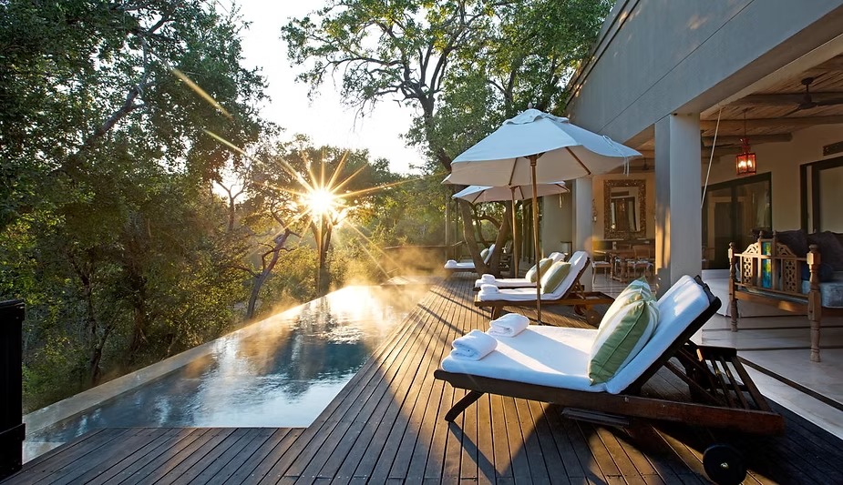 The private pool deck at Africa House, Royal Malewane, with sun through the trees