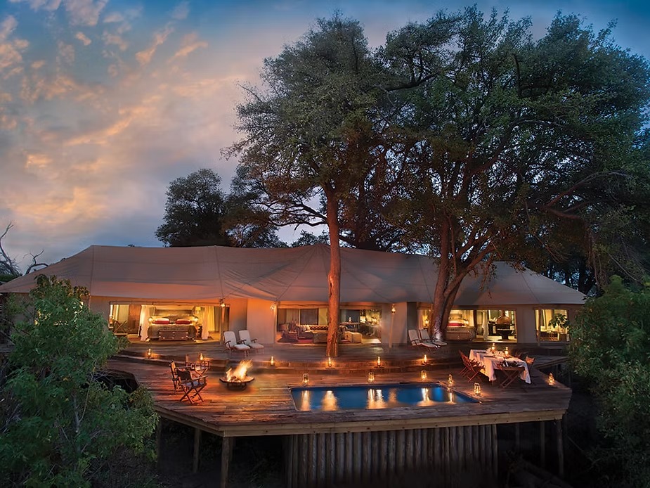 The Zarafa Dhow Suite lit at dusk beside the Selinda Spillway in Botswana