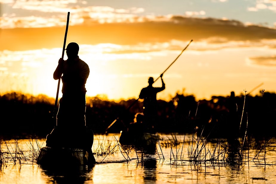 Mokoro polers silhouetted against the sunset in the Okavango Delta