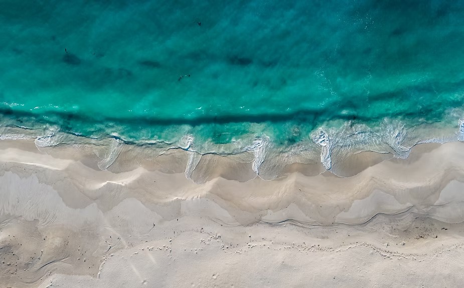 Turquoise water washing over white sand, seen from above