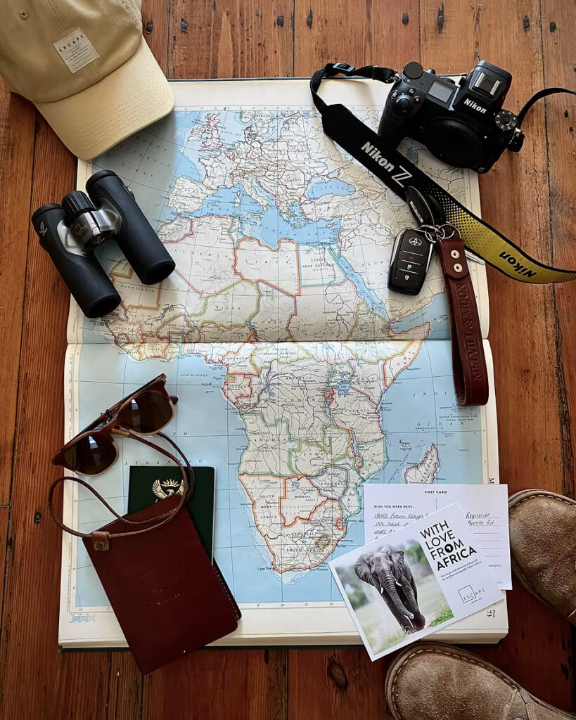 Safari kit laid out: a map of Africa, camera, binoculars, passport and field notes