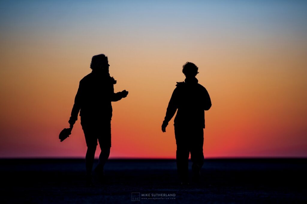 Two figures silhouetted against the last light of an African sunset